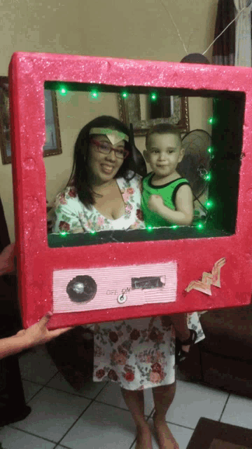a woman holding a child in front of a pink box that says off