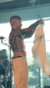 a man with a tattoo on his chest holds a white shirt