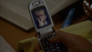 someone is holding a flip phone with a picture of a man on the screen