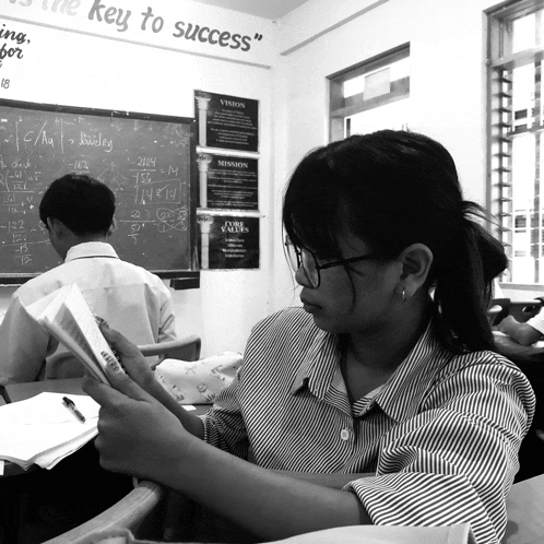 a girl sits at a desk in front of a blackboard that says " the key to success " on it