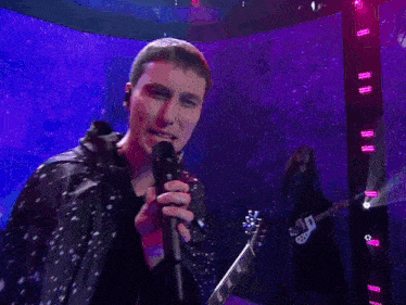 a man playing a drum in front of a purple and blue background