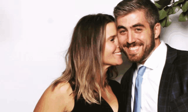 a man and a woman are posing for a photo and the woman is kissing the man on the cheek
