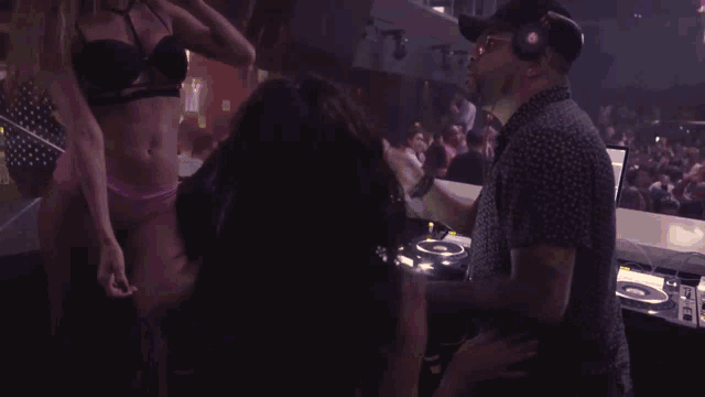 a man wearing headphones talks to a woman in a bikini in a club