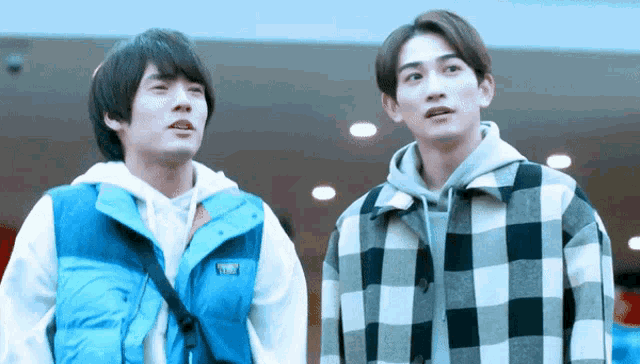 two young men in plaid jackets are standing next to each other and looking up .