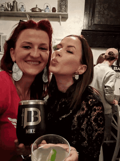 two women posing for a picture with a cup that says mike