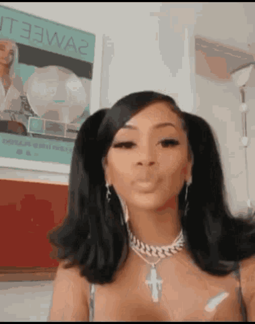 a woman with pigtails is wearing a necklace and earrings and making a face .