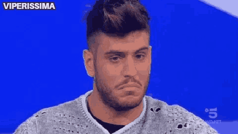 a man with a beard is wearing a sweater and making a funny face .