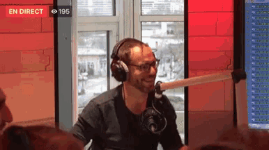 a man wearing headphones stands in front of a microphone in front of a sign that says en direct 195
