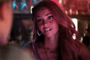 a woman with pink hair and hoop earrings is sitting in a bar .