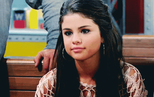 a woman with hoop earrings is sitting on a wooden bench