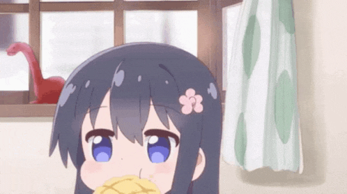 a little girl with blue eyes and a flower on her head is eating a sandwich in front of a window .