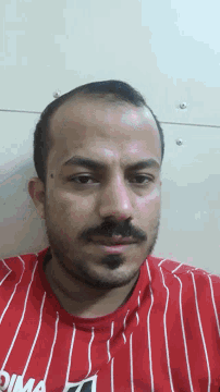 a man with a beard wearing a red and white striped shirt that says puma on it