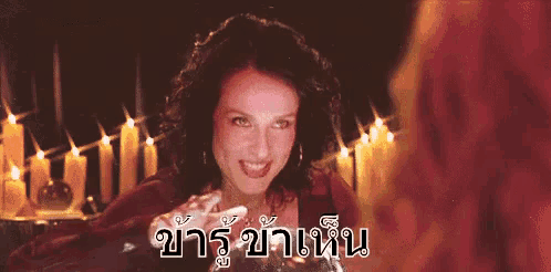 a woman is smiling in front of a table with candles and the words in a foreign language .