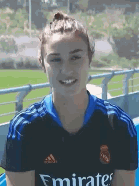 a woman wearing a black emirates jersey smiles