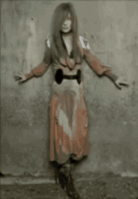 a woman in a red dress stands in front of a wall with her arms outstretched