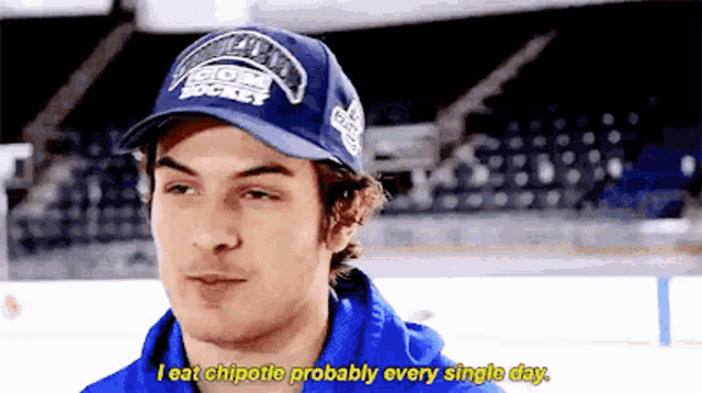 a man wearing a blue hat that says ' i eat chipotle probably every single day ' on it