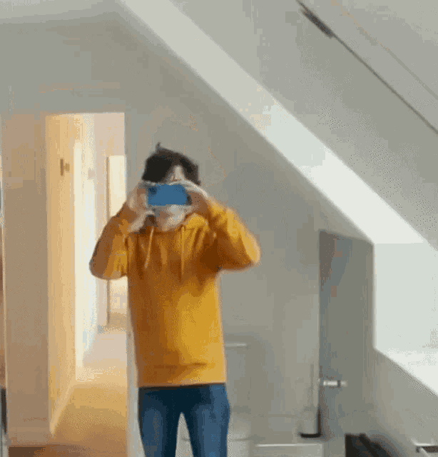 a man in a yellow hoodie is taking a picture of himself