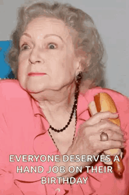 an elderly woman is holding a hot dog in her hands and saying `` everyone deserves a hand job on their birthday '' .