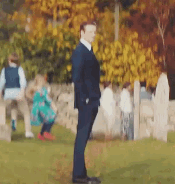 a man in a suit is standing in a park with a little girl in a green dress .