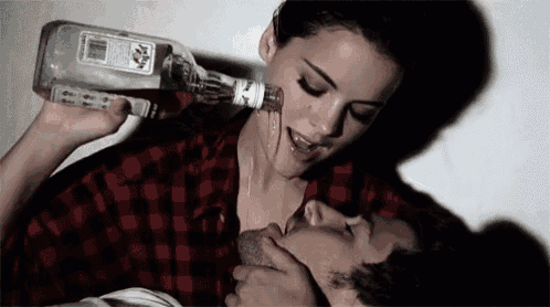 a woman is drinking from a bottle with a label that says tequila