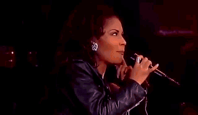 a woman is singing into a microphone on a stage .
