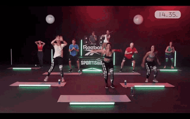 a group of people are jumping in front of a sign that says reebok