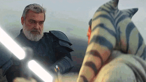 a man with a beard is standing next to a zebra with a lightsaber .