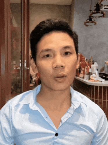 a man wearing a light blue shirt with a black button