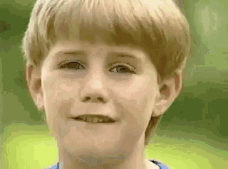 a young boy is making a funny face with his mouth open and his eyes closed .