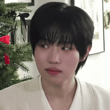 a close up of a person 's face next to a christmas tree