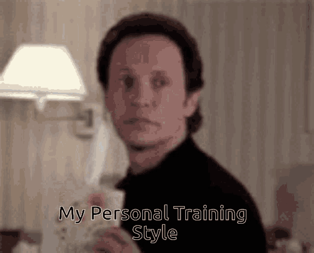 a man in a black turtleneck is holding a piece of paper with the words `` my personal training style '' written on it .