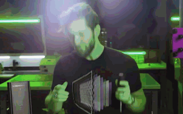 a man in a black t-shirt holds a device that says ' armoury ' on it