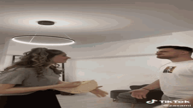 a man and a woman are playing with a tortilla and a tiktok account is visible