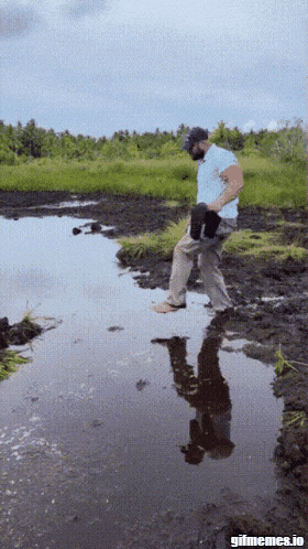 a man is walking through a muddy puddle with gifmemes.io in the corner