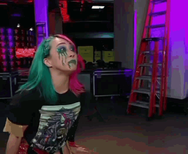 a woman with green and pink hair is making a face with her hands