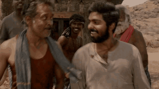 a man with a beard and a towel around his neck talks to another man
