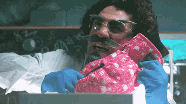 a man wearing glasses and a mustache is holding a pink item