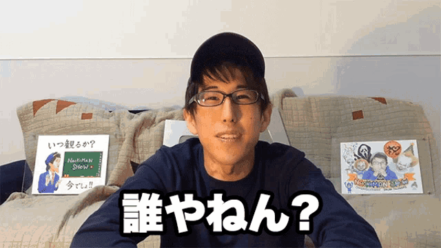 a man wearing glasses and a black hat is sitting in front of a chalkboard that says nishiman shokunin
