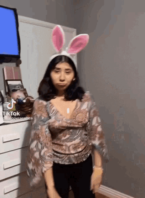 a woman wearing bunny ears is standing in front of a television .
