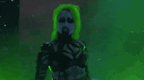 a person with green hair and a beard is standing in front of a green wall