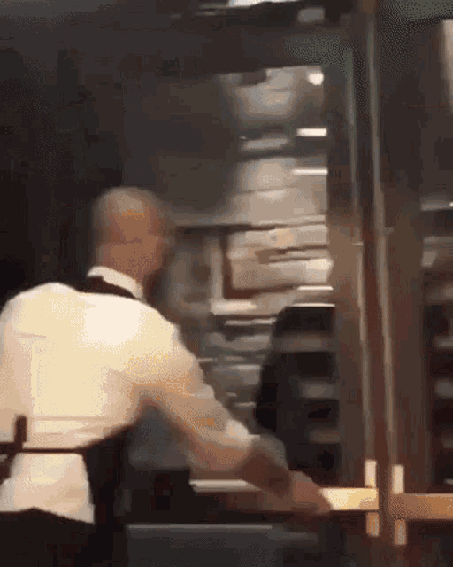 a man in a white shirt and black apron is standing in front of a door .