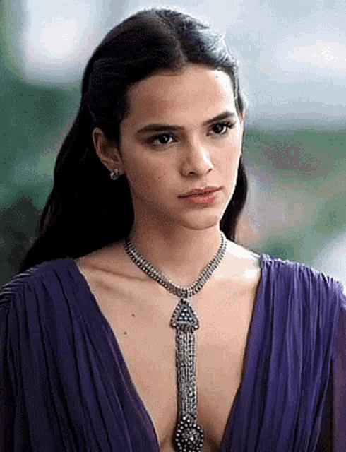 a woman wearing a purple dress and a necklace