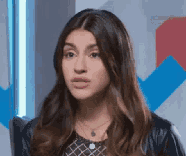 a woman with long hair is making a funny face while wearing a leather jacket .