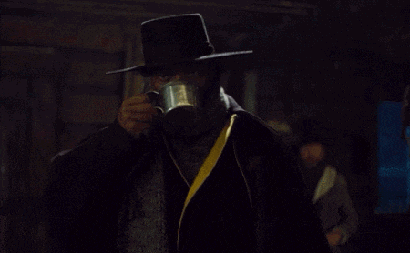 a man wearing a hat and scarf holds a cup of coffee
