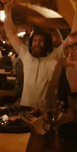 a man with a beard wearing a helmet holds his arms up in the air