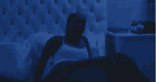 a man is laying in a bed with a nightstand in the background .