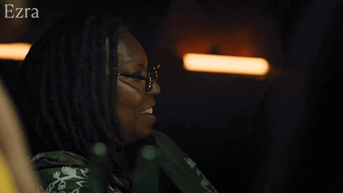 a woman with dreadlocks is smiling and the word ezra is on the bottom right