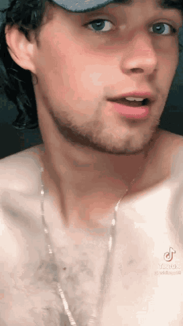 a man without a shirt is wearing a hat and a chain