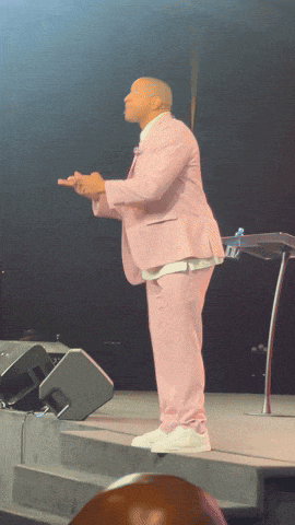 a man in a pink suit is standing on stage