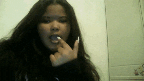 a woman with long white nails is making a rude gesture